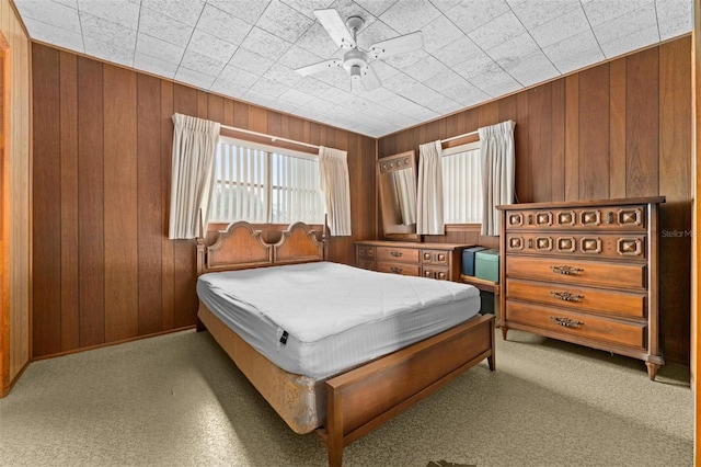 carpeted bedroom with ceiling fan and wooden walls