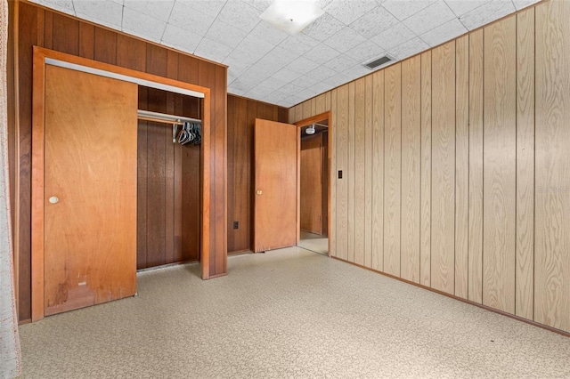 unfurnished bedroom with a closet and wooden walls