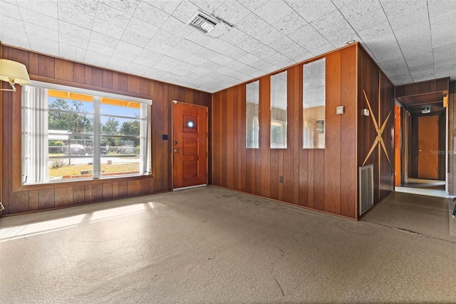 carpeted spare room featuring wood walls