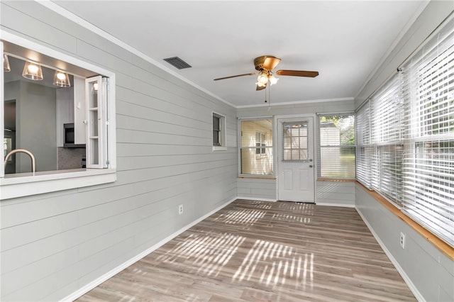 unfurnished sunroom featuring ceiling fan and sink