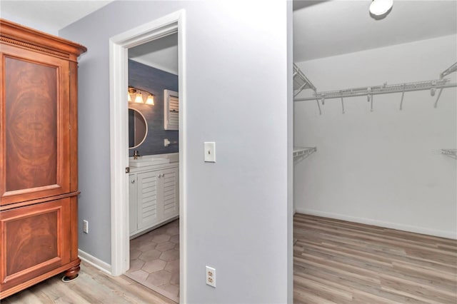 walk in closet with sink and light hardwood / wood-style flooring