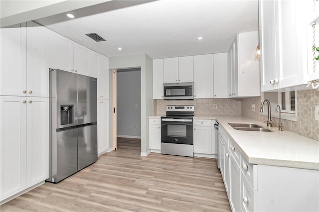 kitchen with light wood-type flooring, sink, stainless steel appliances, and white cabinetry