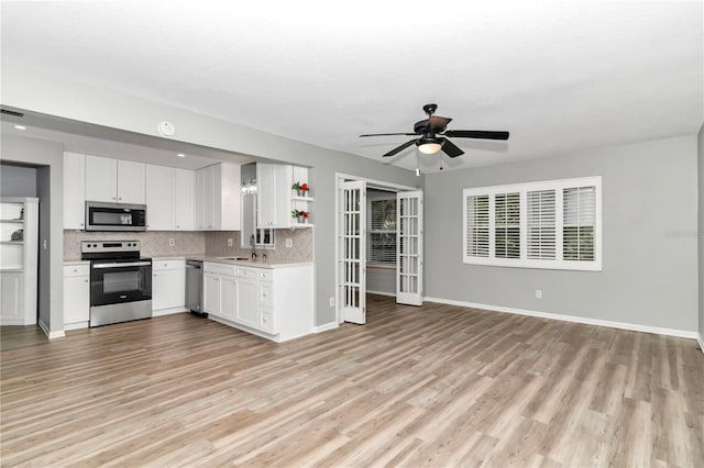 kitchen featuring white cabinets, stainless steel appliances, decorative backsplash, light wood-type flooring, and ceiling fan