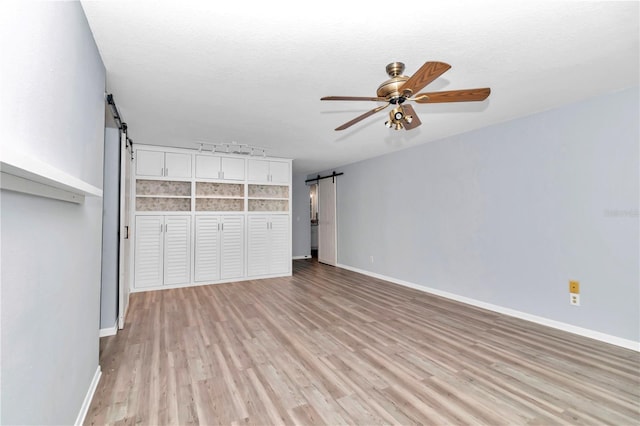 interior space with a textured ceiling, a closet, light wood-type flooring, ceiling fan, and a barn door