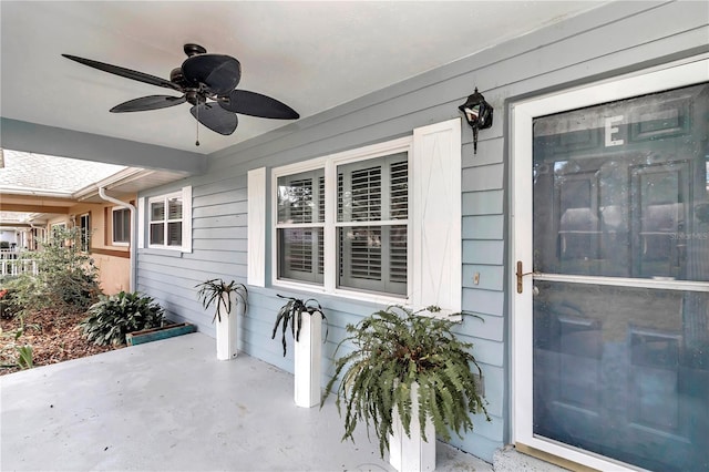 view of exterior entry with ceiling fan and a patio