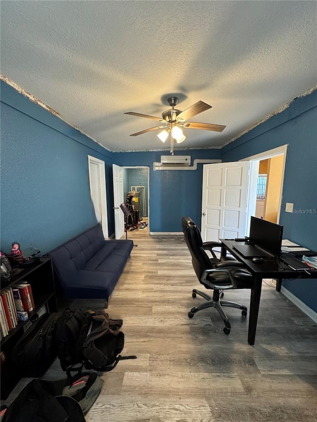 home office with a textured ceiling, light hardwood / wood-style flooring, ceiling fan, and an AC wall unit