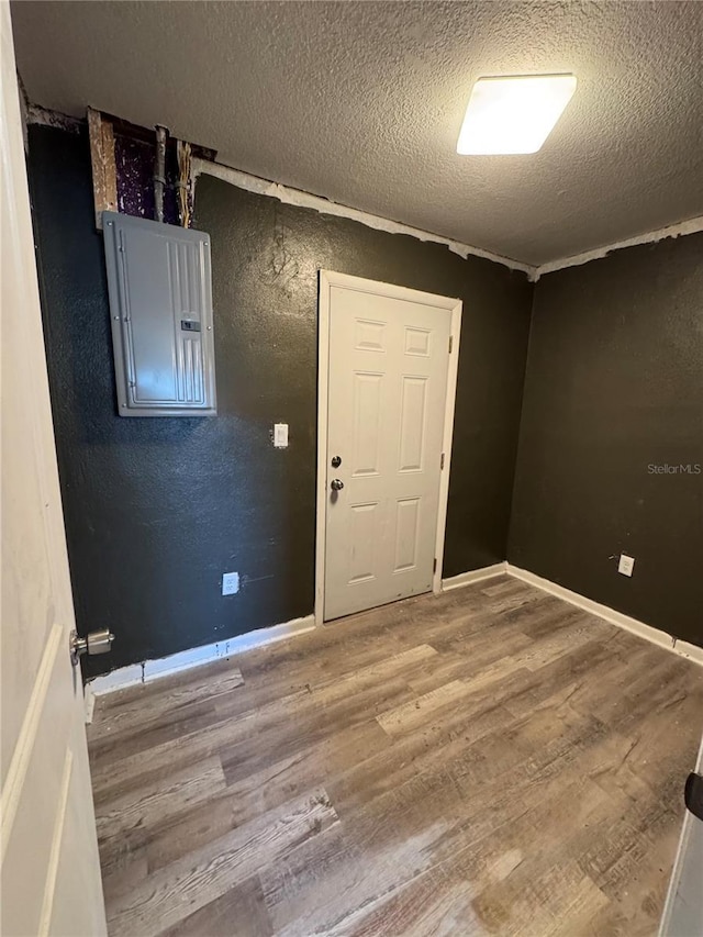 interior space with a textured ceiling, electric panel, and hardwood / wood-style flooring