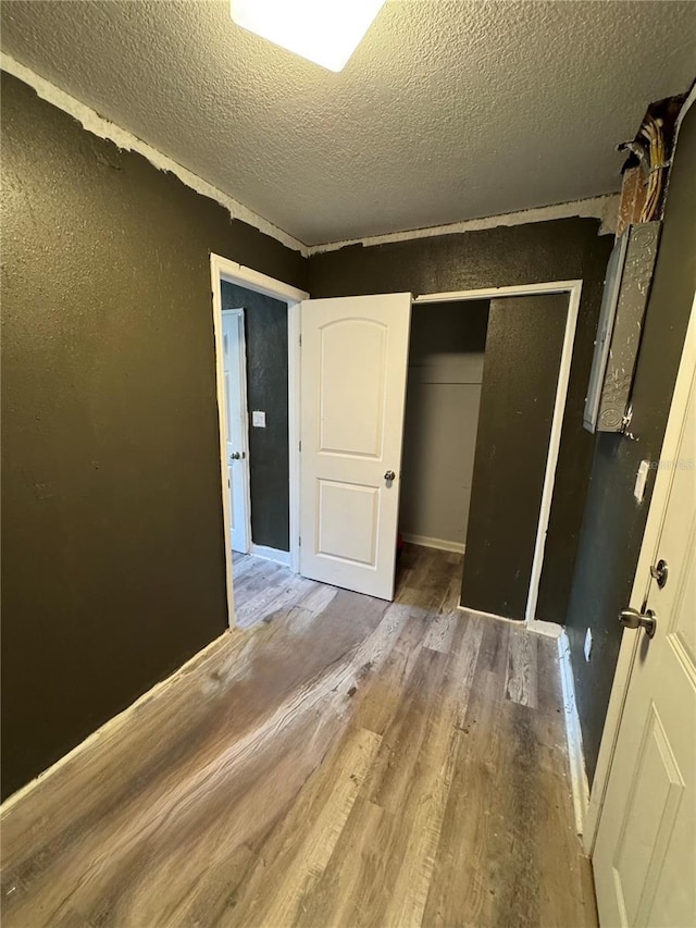 unfurnished bedroom with a closet, hardwood / wood-style floors, and a textured ceiling