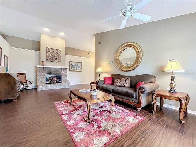 living room with a textured ceiling, ceiling fan, a fireplace, and dark hardwood / wood-style floors