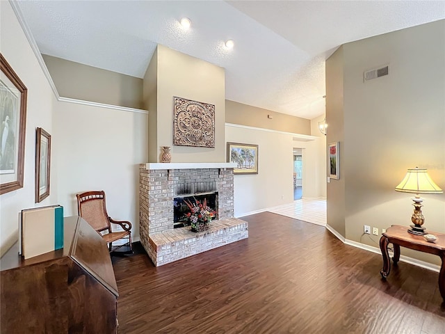 living room with a textured ceiling, a brick fireplace, and dark wood-type flooring