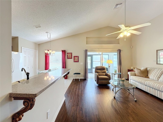 living room featuring sink, dark wood-type flooring, a textured ceiling, vaulted ceiling, and ceiling fan with notable chandelier