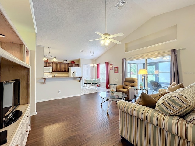 living room with ceiling fan with notable chandelier, a textured ceiling, dark wood-type flooring, and lofted ceiling