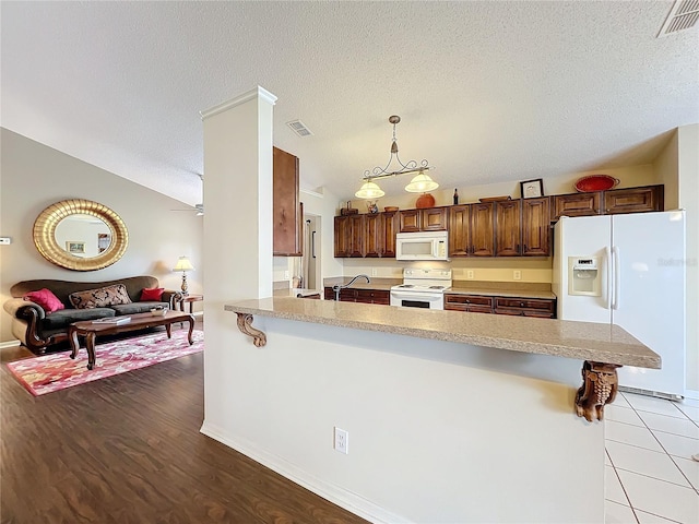 kitchen with pendant lighting, a kitchen breakfast bar, white appliances, and kitchen peninsula