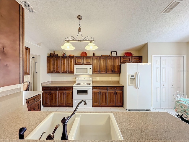 kitchen with white appliances, sink, light tile patterned floors, a textured ceiling, and decorative light fixtures