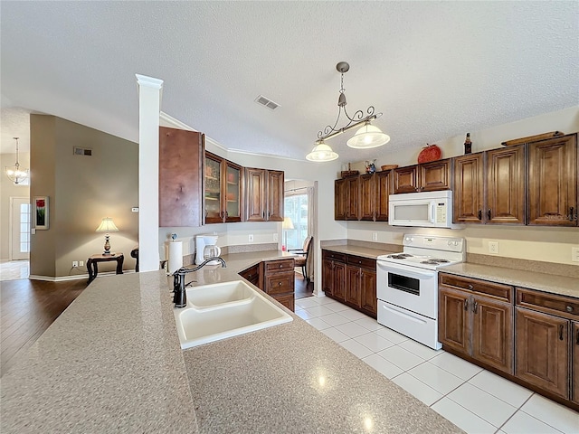 kitchen with lofted ceiling, white appliances, sink, decorative light fixtures, and light hardwood / wood-style floors