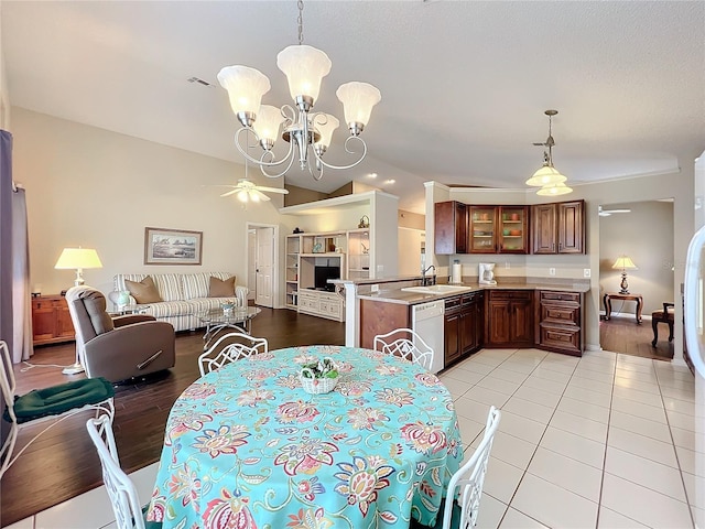 dining room with lofted ceiling, sink, light tile patterned floors, and ceiling fan with notable chandelier