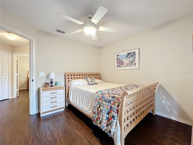 bedroom with ceiling fan, dark wood-type flooring, and a textured ceiling