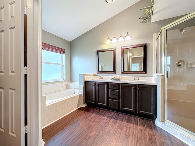 bathroom featuring vanity, wood-type flooring, independent shower and bath, and vaulted ceiling