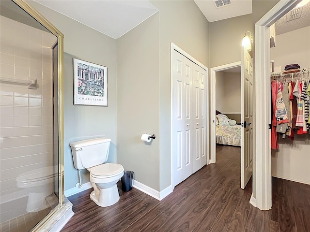 bathroom with wood-type flooring, a shower with shower door, and toilet