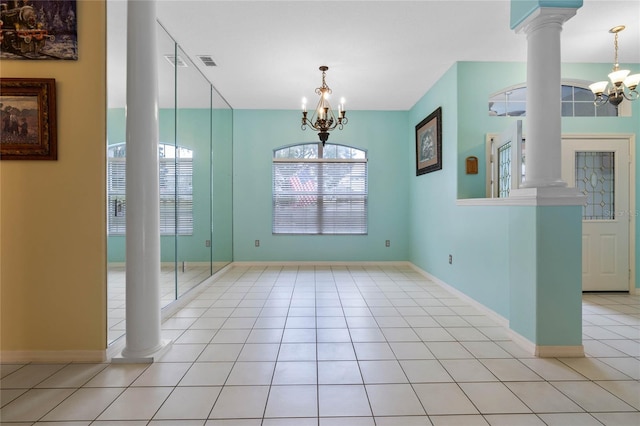 unfurnished dining area with ornate columns, light tile patterned floors, and a notable chandelier