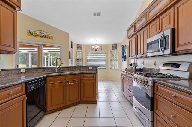 kitchen with sink, dark stone counters, a notable chandelier, and appliances with stainless steel finishes