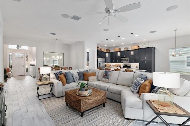 living room featuring ceiling fan with notable chandelier and light hardwood / wood-style floors