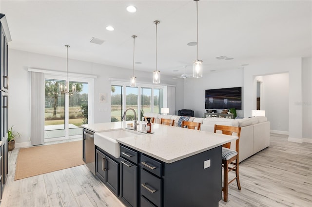 kitchen with a breakfast bar, a sink, light wood-style flooring, and stainless steel dishwasher