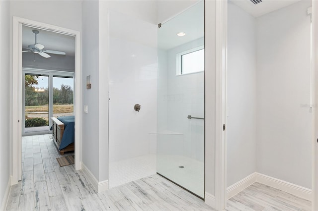 bathroom with ceiling fan, walk in shower, wood finished floors, and baseboards