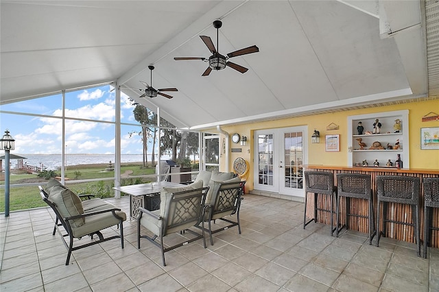 sunroom with ceiling fan, french doors, a water view, and lofted ceiling