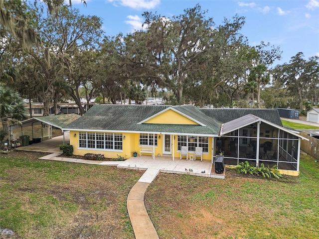 back of property featuring a patio area, a carport, a lawn, and a sunroom