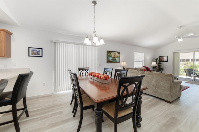 dining area with ceiling fan with notable chandelier, light hardwood / wood-style floors, and vaulted ceiling