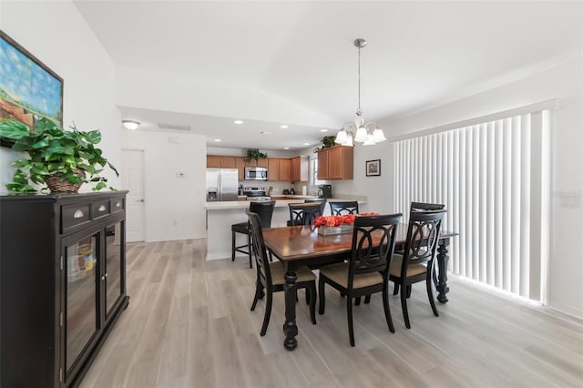 dining area featuring lofted ceiling, light hardwood / wood-style flooring, and a chandelier