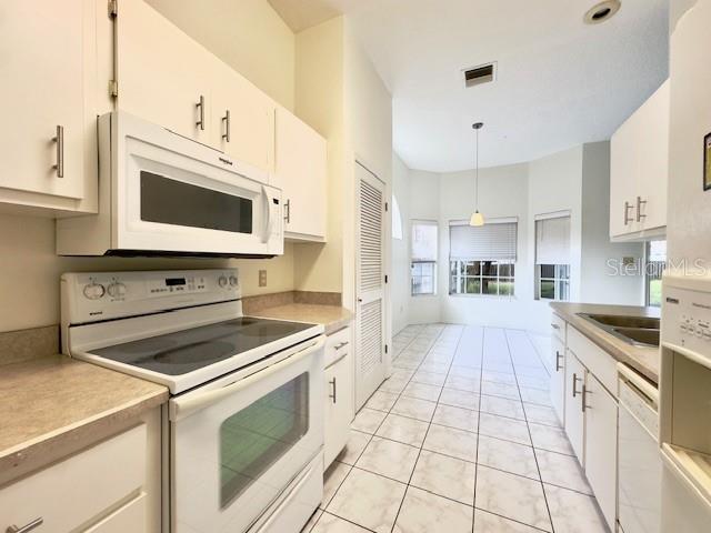 kitchen with white cabinets, decorative light fixtures, white appliances, and sink