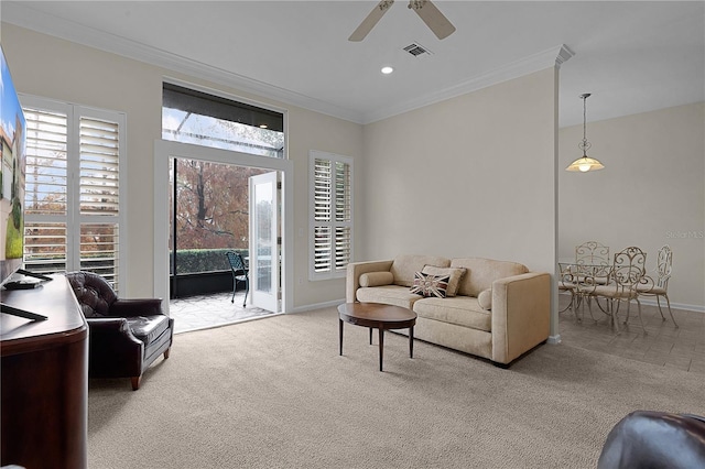 living room with ceiling fan, crown molding, and light colored carpet