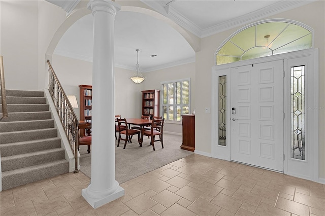 carpeted foyer featuring ornate columns and ornamental molding