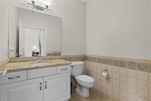 bathroom featuring tile patterned flooring, vanity, tile walls, and toilet