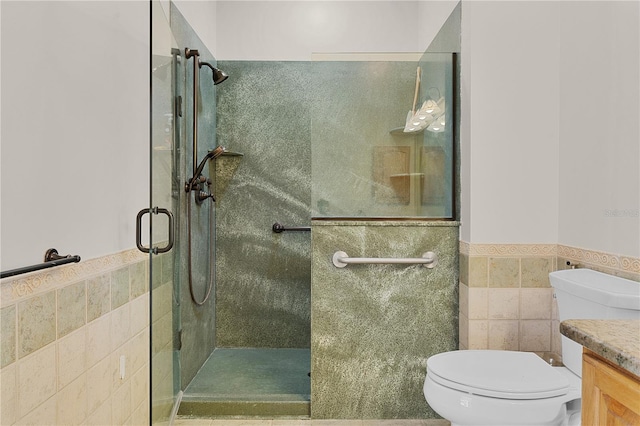 bathroom with vanity, a shower with door, toilet, and tile walls