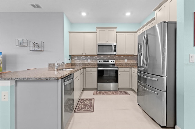 kitchen with sink, stainless steel appliances, tasteful backsplash, kitchen peninsula, and light tile patterned floors