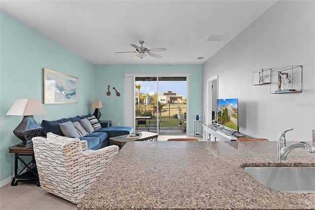 tiled living room with ceiling fan and sink