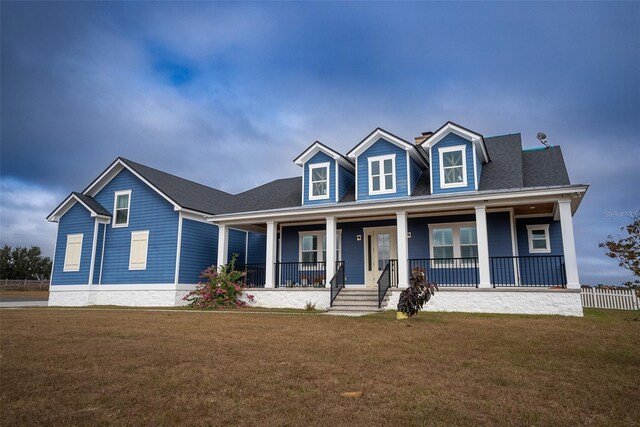 cape cod-style house featuring covered porch and a front lawn