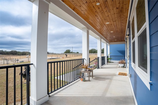 balcony featuring covered porch and a rural view