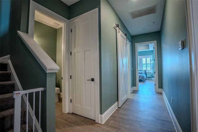 hallway with a barn door and light hardwood / wood-style flooring