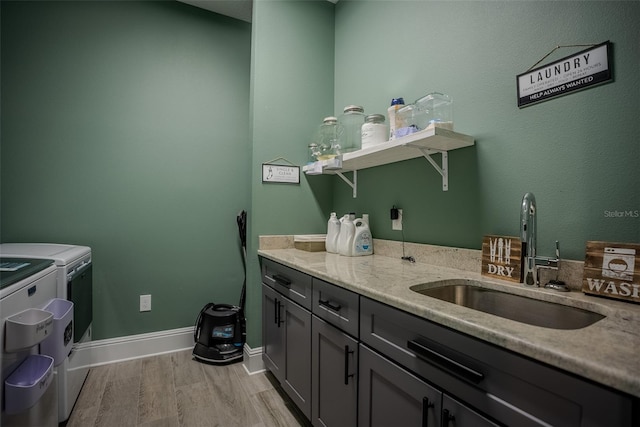 clothes washing area with separate washer and dryer, sink, cabinets, and light hardwood / wood-style flooring