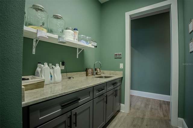 interior space featuring gray cabinetry, light stone counters, sink, and light hardwood / wood-style flooring