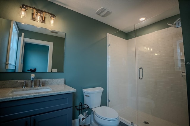 bathroom with vanity, a shower with shower door, and toilet