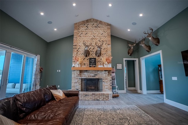 living room with light wood-type flooring, high vaulted ceiling, and a brick fireplace