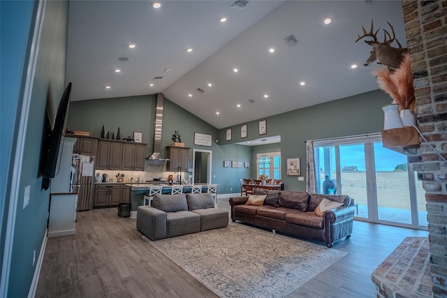 living room with sink, a water view, light hardwood / wood-style floors, and high vaulted ceiling