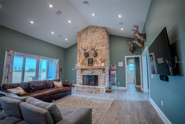 living room featuring light hardwood / wood-style floors, a water view, high vaulted ceiling, and a brick fireplace