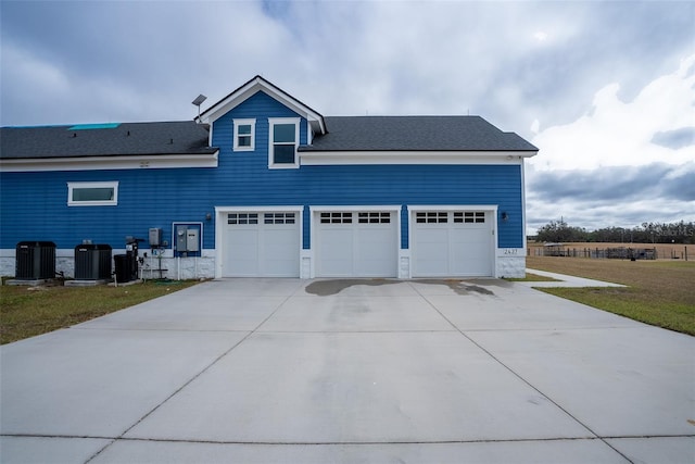 exterior space featuring cooling unit, a garage, and a front lawn