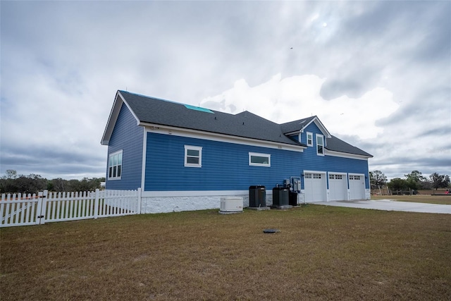 view of side of home with a lawn, a garage, and central AC